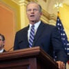 Senate Majority Leader John Thune at a podium in the U.S. Capitol Building, with Speaker Mike Johnson at his side.
