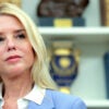 Attorney General Pam Bondi, with a backdrop of bookshelves with law books.