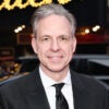 Jake Tapper poses outdoors for a photo while wearing a suit.