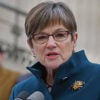 Kansas Gov. Laura Kelly in a blue winter jacket speaks at a microphone