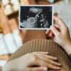 A pregnant woman looks at an ultrasound image of her unborn baby.
