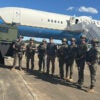 Secretary of Defense Pete Hegseth poses with Fort Bragg police in Fayetteville, North Carolina, with his aircraft as backdrop.