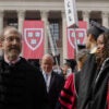 Alan Garber stands wearing a graduation gown and looks out at a crowd.
