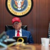 President Trump in a MAGA hat sits at a table in the White House Situation room.