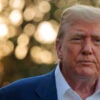 Close-up of President Trump in blue jacket and open-collar white shirt outside the White House.