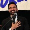 Zohran Mamdani puts his hand on his heart while addressing supporters.
